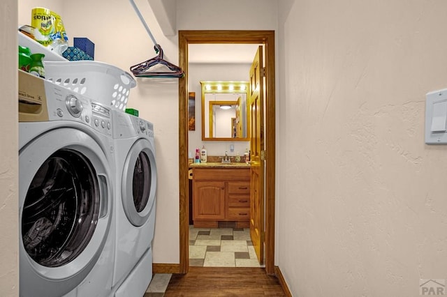 laundry area featuring wood finished floors, baseboards, washing machine and clothes dryer, laundry area, and a sink