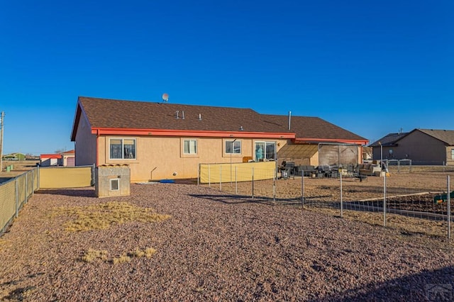 back of house featuring roof with shingles and a fenced backyard