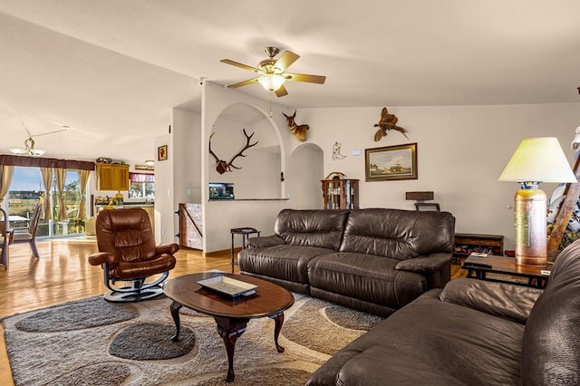 living area featuring a ceiling fan, vaulted ceiling, arched walkways, and light wood-type flooring