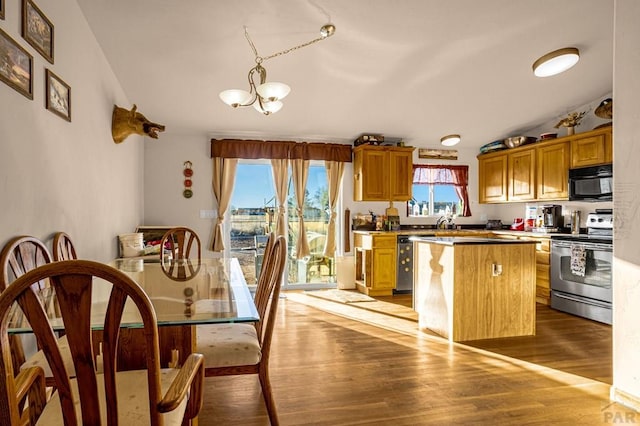 kitchen featuring wood finished floors, a kitchen island, stainless steel range with electric cooktop, vaulted ceiling, and black microwave