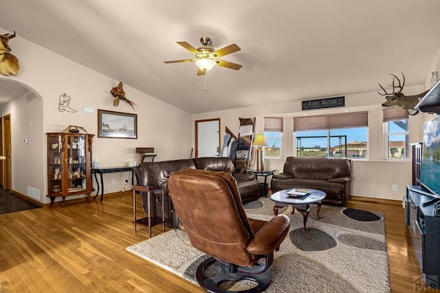 living area with visible vents, a ceiling fan, wood finished floors, arched walkways, and vaulted ceiling