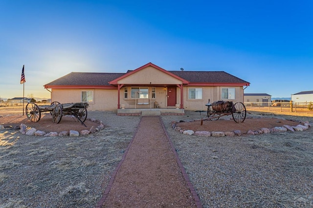 back of property at dusk featuring stucco siding and fence