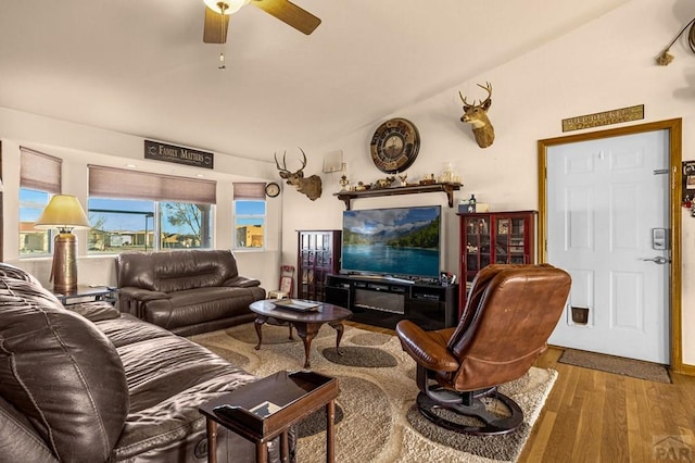 living room featuring vaulted ceiling, a ceiling fan, and wood finished floors