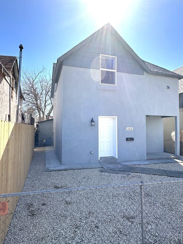 back of property with stucco siding and fence