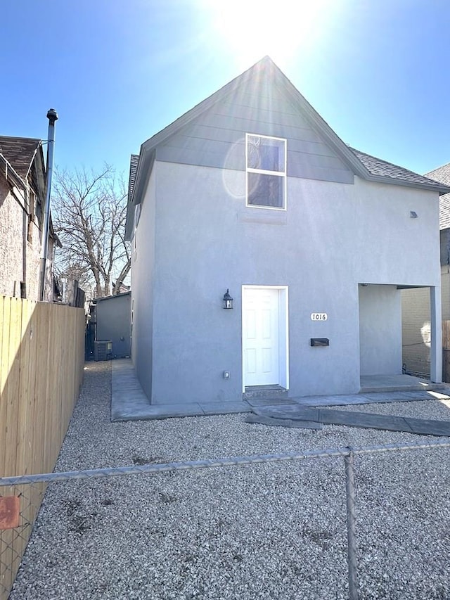 rear view of property with fence and stucco siding