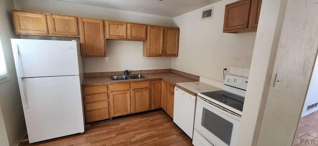 kitchen with visible vents, white appliances, light countertops, a sink, and light wood finished floors