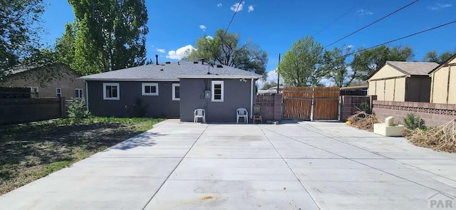 rear view of property with fence, a gate, a patio, and stucco siding