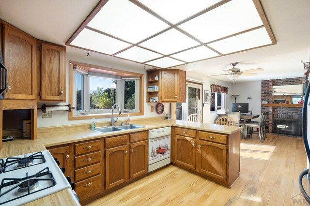 kitchen with a sink, a peninsula, white appliances, and light countertops