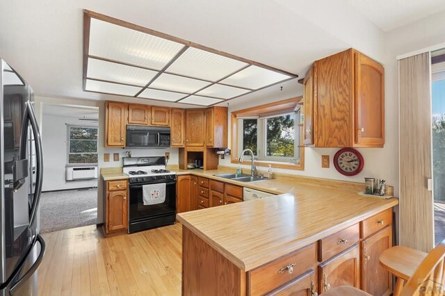 kitchen with black microwave, light countertops, a sink, and gas range oven