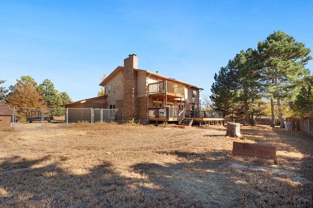 rear view of property featuring a chimney, fence, and a deck