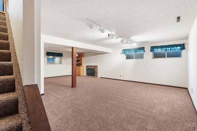 finished basement with baseboards, visible vents, carpet, stairs, and a textured ceiling