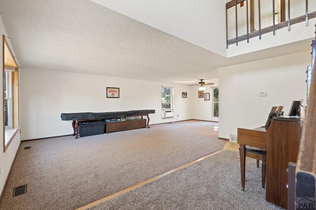 interior space featuring a ceiling fan, visible vents, a textured ceiling, and baseboards