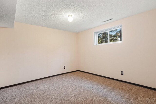 unfurnished room featuring carpet floors, visible vents, a textured ceiling, and baseboards