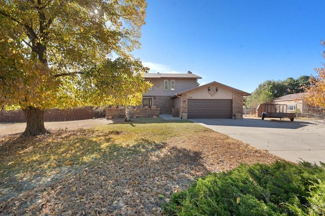 view of front of property featuring a garage, brick siding, fence, driveway, and stucco siding