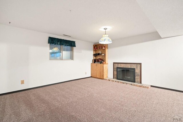 unfurnished living room featuring carpet floors, a brick fireplace, a textured ceiling, and baseboards