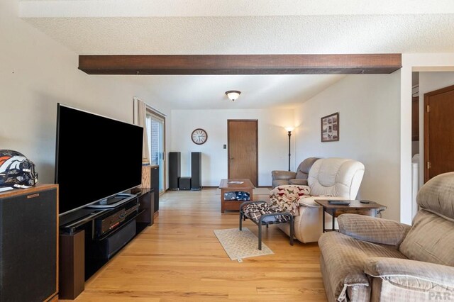 living room with light wood-style flooring, a textured ceiling, and beam ceiling