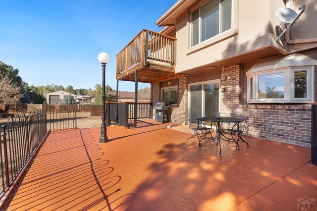 wooden terrace featuring grilling area, a patio area, and fence