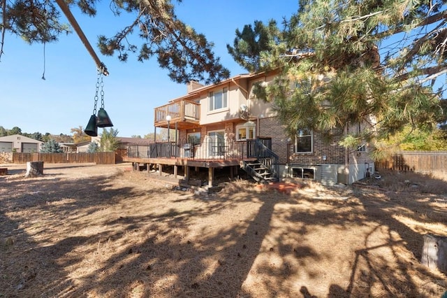 back of house with a chimney, brick siding, fence, and a deck