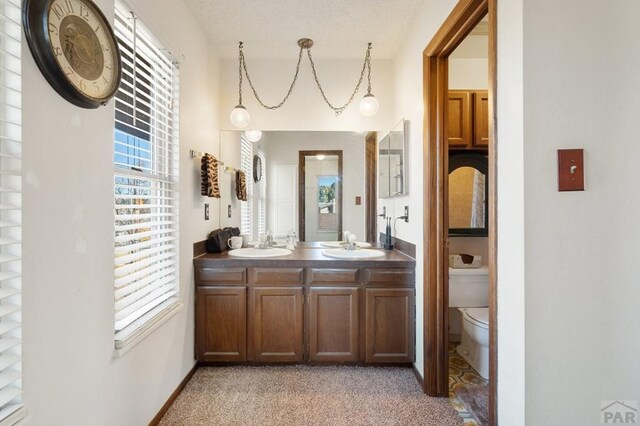 bathroom with toilet, double vanity, and a sink