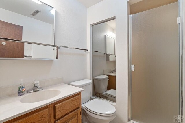 full bath featuring toilet, visible vents, a shower stall, and vanity