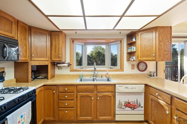 kitchen featuring gas stove, light countertops, white dishwasher, and a sink