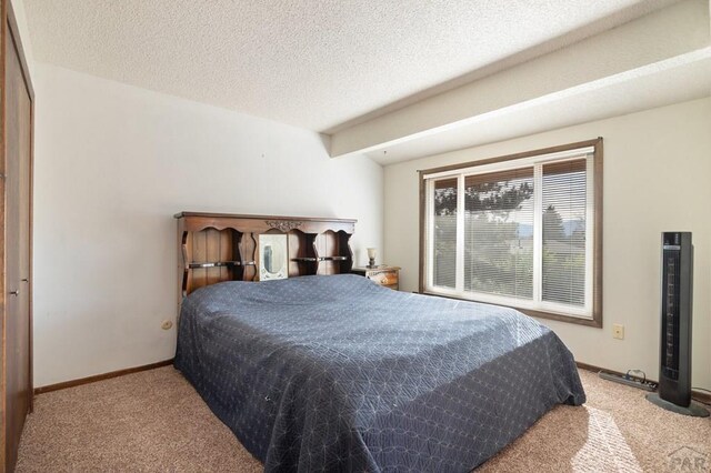 carpeted bedroom featuring lofted ceiling with beams, baseboards, and a textured ceiling