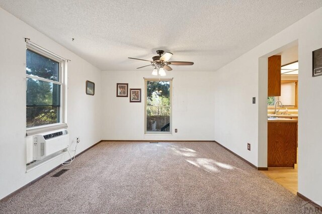 empty room featuring light carpet, baseboards, visible vents, cooling unit, and a sink