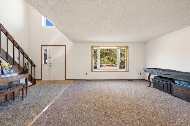 living room with stairs, a textured ceiling, carpet, and baseboards