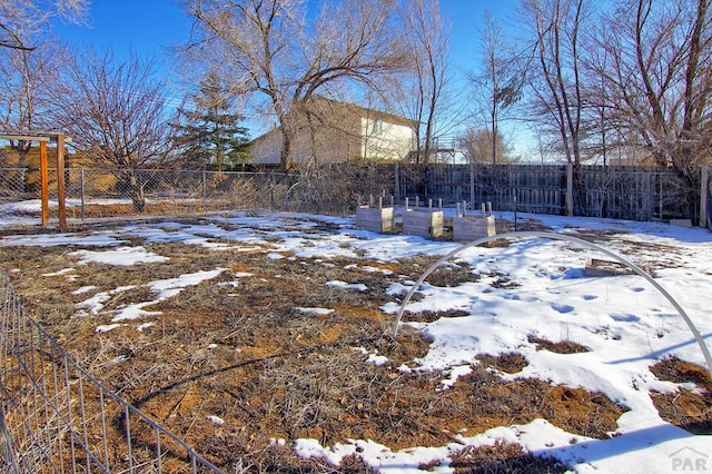 yard covered in snow with a garden and fence