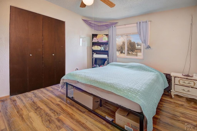 bedroom with a closet, a textured ceiling, ceiling fan, and wood finished floors