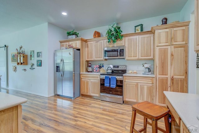 kitchen with appliances with stainless steel finishes, light countertops, light brown cabinets, and light wood-style floors