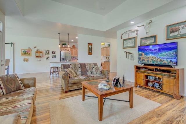 living room featuring recessed lighting, baseboards, and light wood finished floors