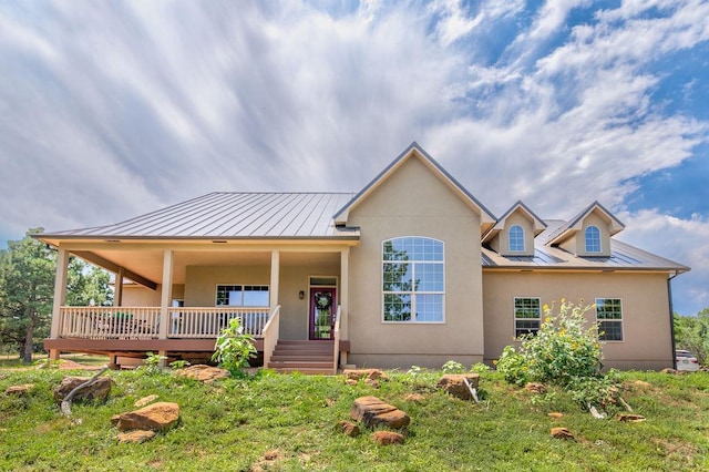 view of front of home with a standing seam roof, a porch, metal roof, and stucco siding