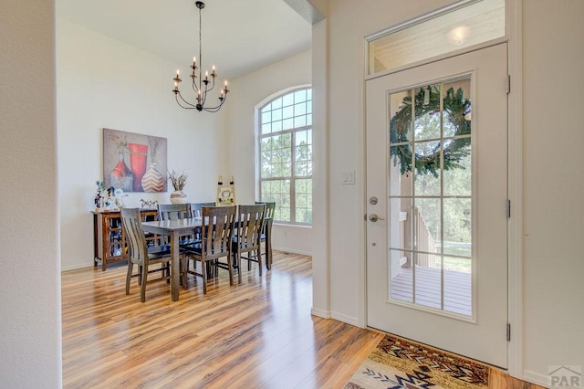 dining room featuring light wood finished floors, baseboards, and an inviting chandelier