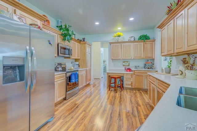 kitchen featuring stainless steel appliances, recessed lighting, light countertops, light wood-style flooring, and light brown cabinets