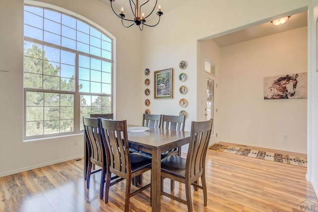 dining room featuring an inviting chandelier, baseboards, and light wood-style floors