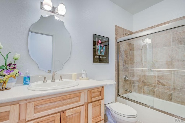 bathroom with toilet, bath / shower combo with glass door, and vanity