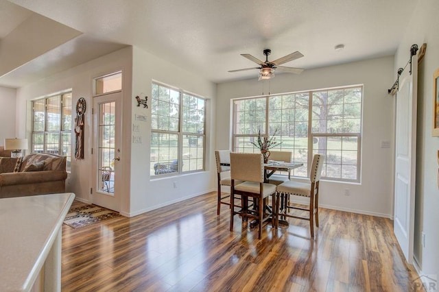 dining space with a healthy amount of sunlight, a barn door, and wood finished floors