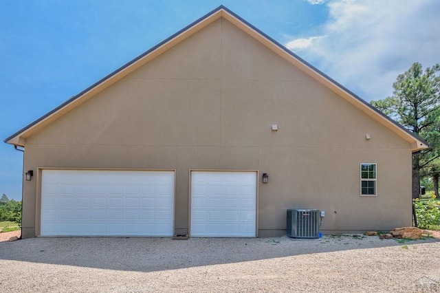 view of home's exterior featuring stucco siding, a detached garage, and central air condition unit