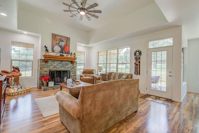 living room with light wood finished floors, baseboards, a ceiling fan, a fireplace, and recessed lighting