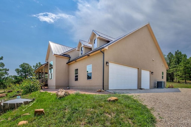 view of side of property with metal roof, an attached garage, gravel driveway, and stucco siding