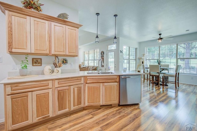 kitchen featuring light brown cabinets, a sink, light wood-type flooring, dishwasher, and a peninsula