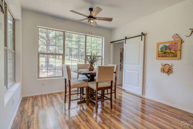 dining area with wood finished floors, plenty of natural light, baseboards, and a barn door