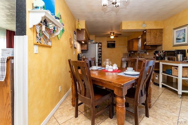 dining space with light tile patterned floors, ceiling fan, and baseboards