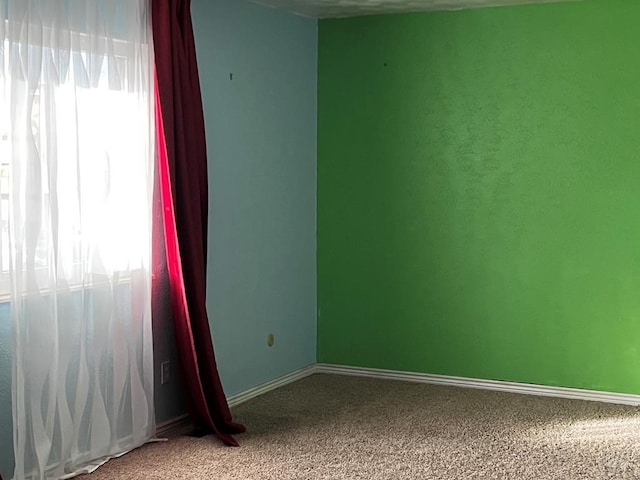 unfurnished room featuring carpet floors and baseboards