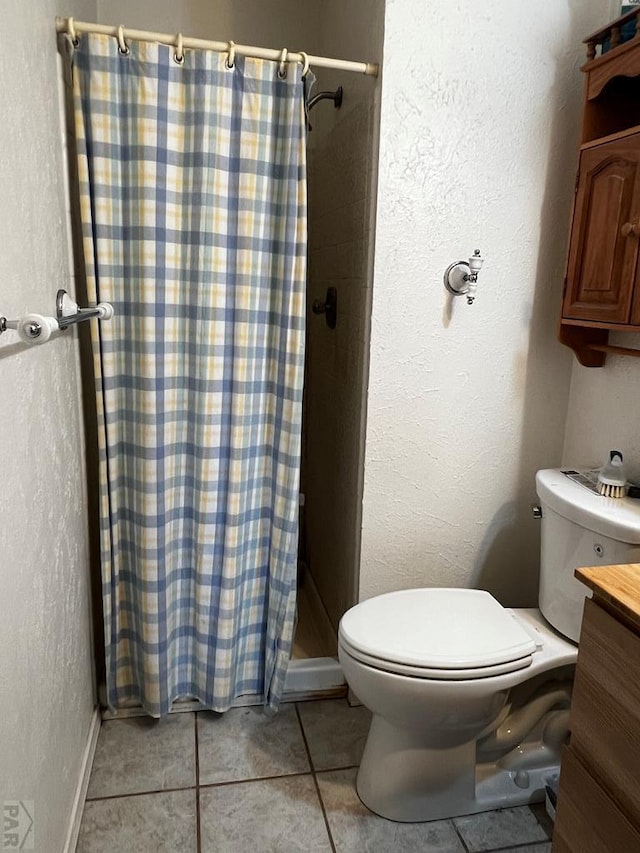 full bathroom featuring tile patterned flooring, toilet, vanity, baseboards, and a stall shower