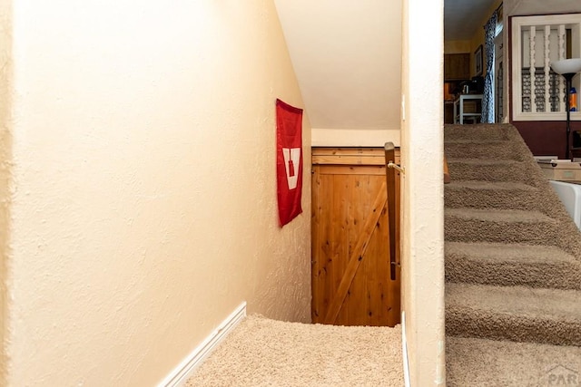 staircase with vaulted ceiling and a textured wall