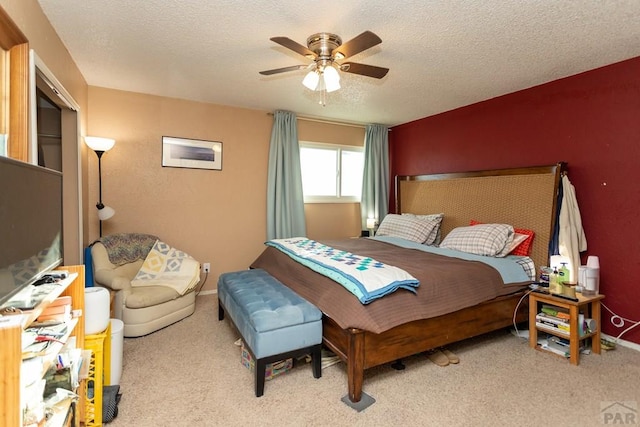 bedroom with ceiling fan, baseboards, a textured ceiling, and light colored carpet