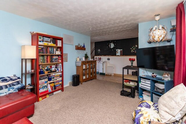 living room with carpet floors, radiator, a textured ceiling, and baseboards