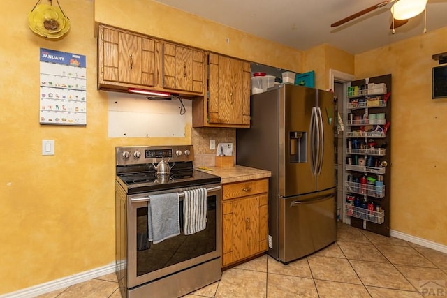 kitchen featuring stainless steel appliances, brown cabinets, light countertops, and light tile patterned flooring